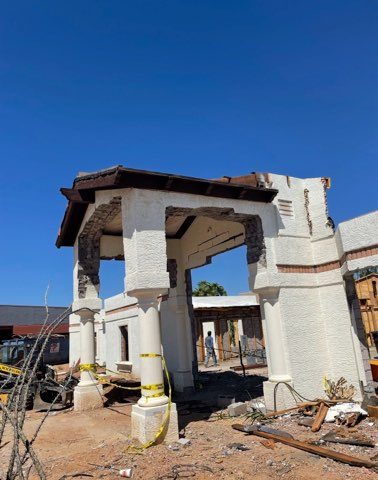 Partial demolition of a stucco commercial building with exposed columns