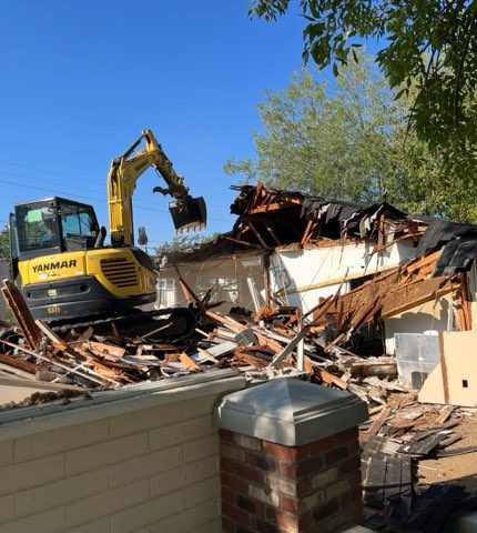 Excavator finishing a demolition job with debris sorted for hauling