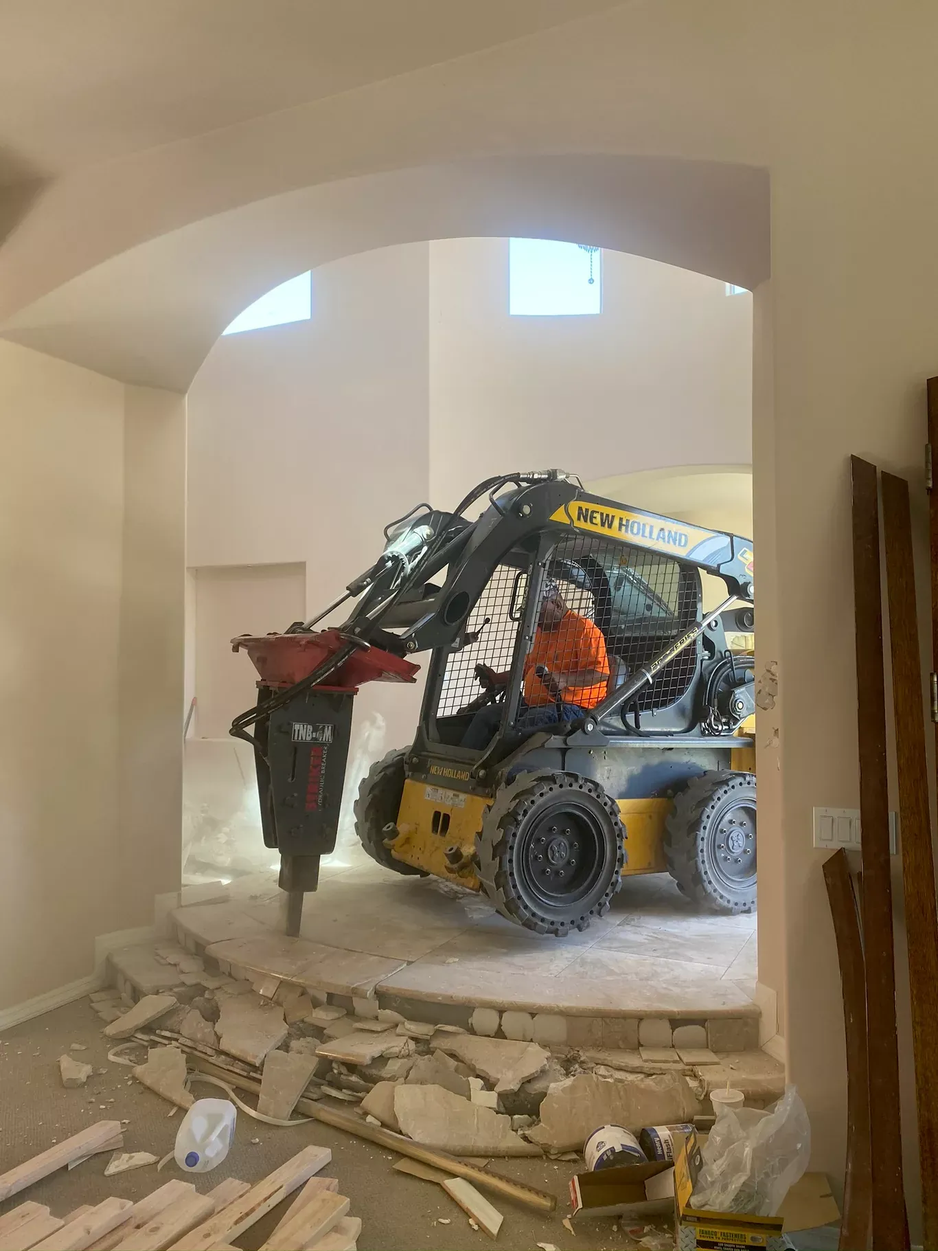 Skid steer with hydraulic breaker demolishing an interior floor