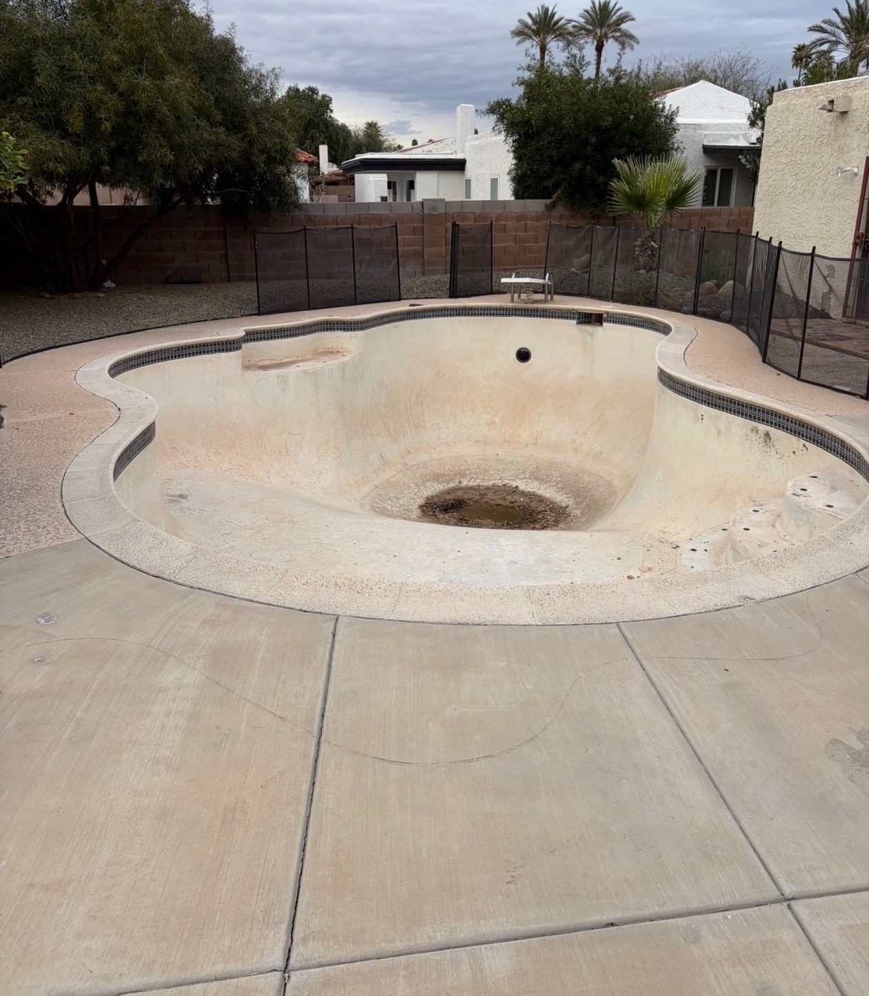 Empty freeform pool with tile coping before demolition at a Phoenix-area home