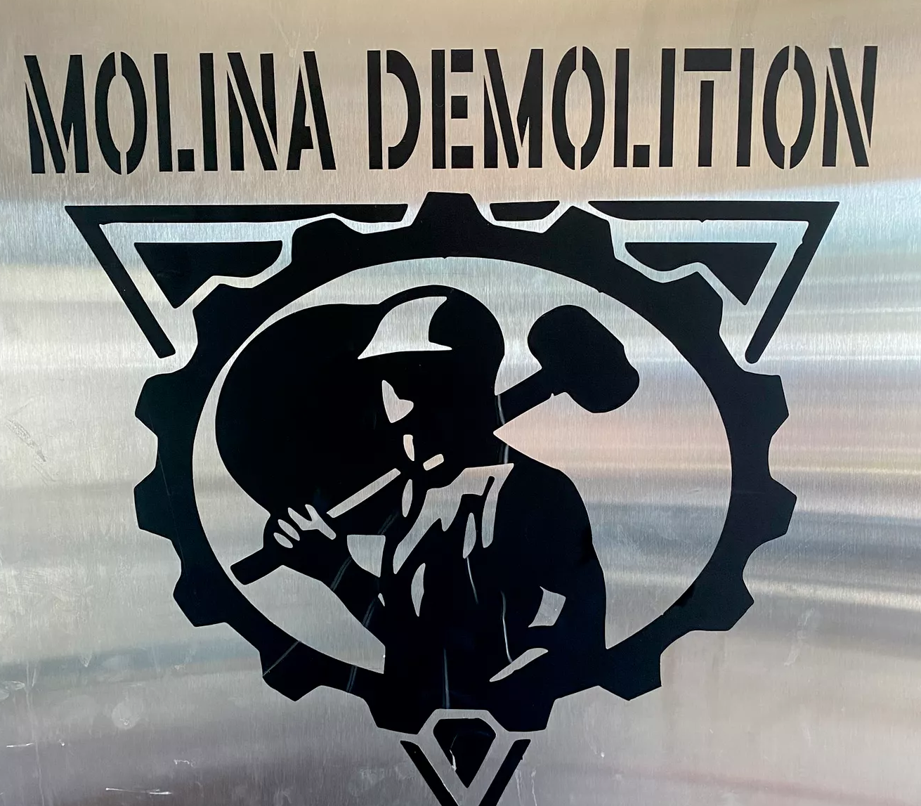 The Molina Demolition brushed-steel engraved sign — the real company logo